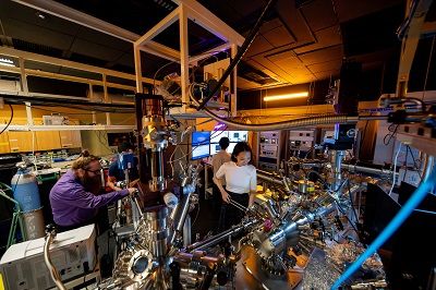 The experimental setup at OIST, using the world-leading time- and angle-resolved photoemission spectroscopy (TR-ARPES) microscope, which features a proprietary, tabletop extreme ultraviolet (XUV) source, capable of imaging the electrons and excitons at femtosecond (fs) timescales. Courtesy of Jeff Prine and Andrew Scott/OIST.